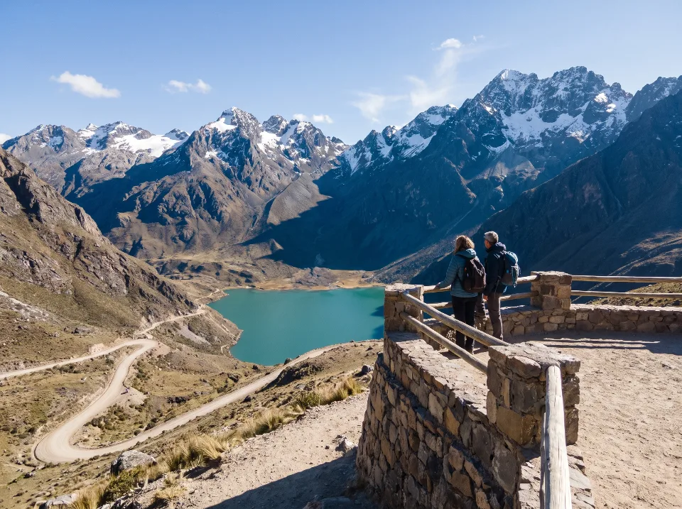 Viajantes observam um lago cercado por montanhas andinas.